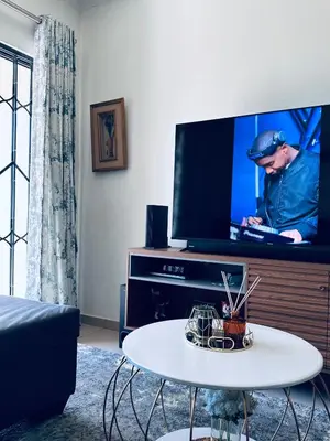 a living room with a tv and a white table at Luxury Apartment At Erand Gardens Midrand in Midrand