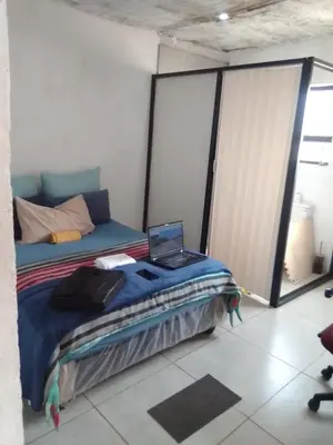 a bedroom with a bed with a laptop on it at Mokoena Village guesthouse in Akasia