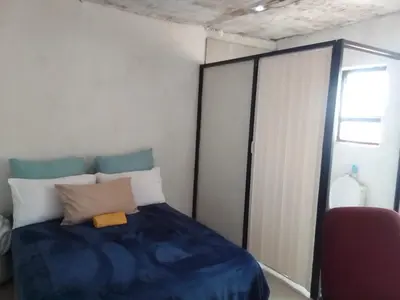 a bedroom with a blue bed and a red chair at Mokoena Village guesthouse in Akasia