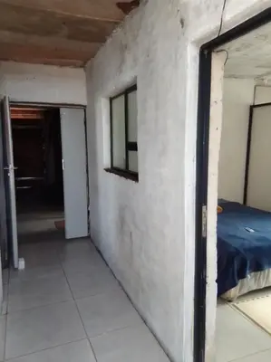 an empty room with a bed and a window at Mokoena Village guesthouse in Akasia