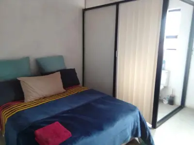 a bedroom with a blue bed with a red pillow at Mokoena Village guesthouse in Akasia
