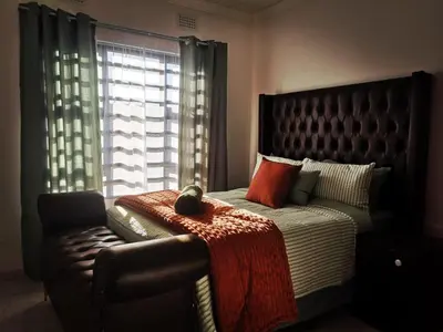 a bedroom with a bed and a chair and a window at Carissa Street Self-catering Units in Burgersfort