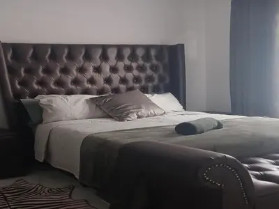 a bedroom with a large bed with a leather headboard at Carissa Street Self-catering Units in Burgersfort
