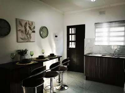 a kitchen with bar stools and a clock on the wall at Carissa Street Self-catering Units in Burgersfort