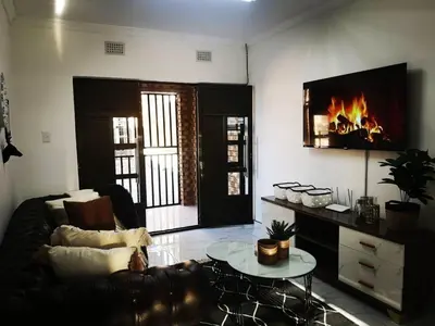 a living room with a leather couch and a fireplace at Carissa Street Self-catering Units in Burgersfort
