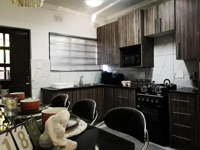 a kitchen with wooden cabinets and a table with chairs at Carissa Street Self-catering Units in Burgersfort
