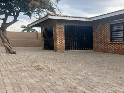 a brick building with a gate and a tree at Carissa Street Self-catering Units in Burgersfort