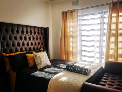 a bedroom with a bed and a couch and a window at Carissa Street Self-catering Units in Burgersfort