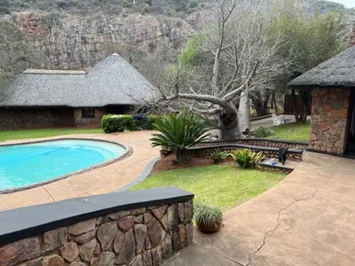 a backyard with a swimming pool and a stone wall at Soutpansberg Lodge Louis Trichardt
