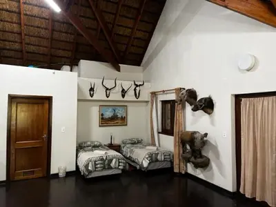 a bedroom with two beds in a room with a wooden ceiling at Soutpansberg Lodge Louis Trichardt