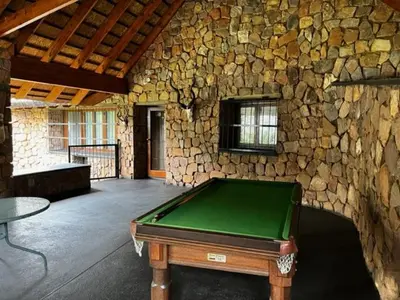 a pool table in a room with a stone wall at Soutpansberg Lodge Louis Trichardt