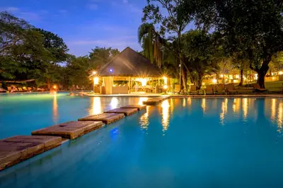 a swimming pool at night with a building in the background at Sanbonani Resort Chalets in Hazyview