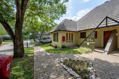a small yellow house with a tree and a driveway at Sanbonani Resort Chalets in Hazyview