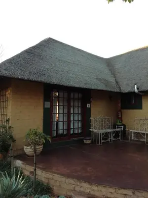 a house with a thatched roof and a patio at Makarios Lodge in Polokwane
