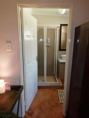 a bathroom with a shower and a glass door at Makarios Lodge in Polokwane