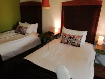 two beds in a hotel room with two lamps at Makarios Lodge in Polokwane