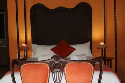 a bedroom with a bed with a large black headboard at Makarios Lodge in Polokwane