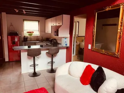 a living room with a white couch and a kitchen at The KinkyKabin in Sandton
