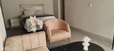 a living room with a bed and a chair and a table at Casa LaMich Garden Venue and Spa in Midrand