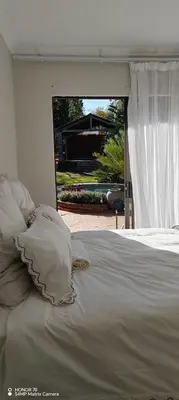 a bed with white sheets and pillows in front of a window at Casa LaMich Garden Venue and Spa in Midrand