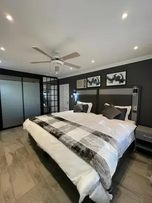 a bedroom with a large bed with a ceiling fan at Antelope Farm Events in Pretoria