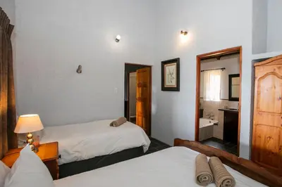 a bedroom with two beds and a bathroom with a sink at Raasblaar at Benlize in Broederstroom