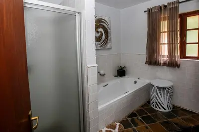 a bathroom with a bath tub and a shower at Raasblaar at Benlize in Broederstroom