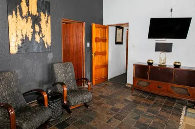 a living room with a tv and two chairs and a dresser at Raasblaar at Benlize in Broederstroom