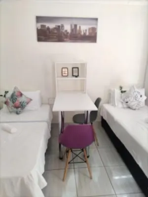 a room with two beds and a desk and a chair at C-Rane Lodge 2 in Phalaborwa