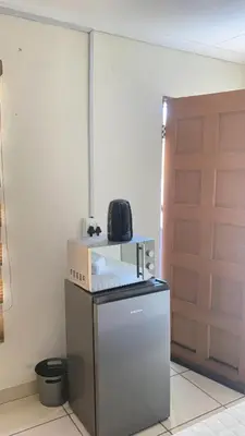 a small refrigerator in a room with a door at C-Rane Lodge 2 in Phalaborwa