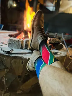 a persons foot in a pair of shoes next to a fire at Wagenbietjieshoek Wilgekraal Farmhouse in Lydenburg
