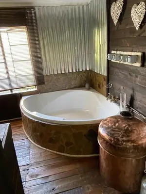a large tub in a bathroom with a wooden floor at Wagenbietjieshoek Wilgekraal Farmhouse in Lydenburg