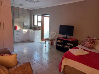 a bedroom with a bed and a tv and a kitchen at 109 Mauser Avenue in Pretoria