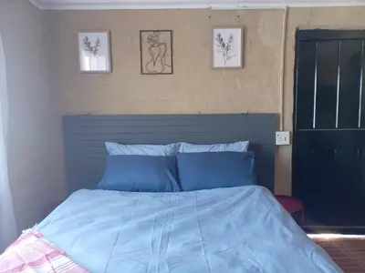 a bedroom with a blue bed with three pictures on the wall at Comfy at Sosha in Soshanguve