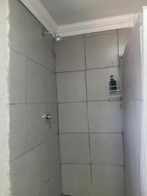 a bathroom with a shower with a white tiled wall at Comfy at Sosha in Soshanguve
