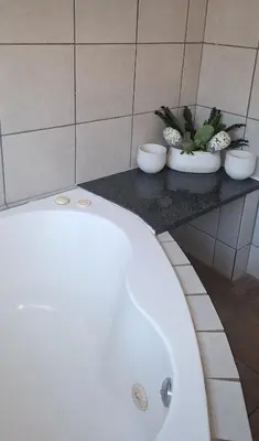 a white bath tub in a bathroom with three plants at Chrysantimum Guest Apartment in Thabazimbi
