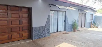 a house with a wooden garage door and a plant at Chrysantimum Guest Apartment in Thabazimbi