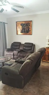 a living room with a brown couch and a table at Chrysantimum Guest Apartment in Thabazimbi