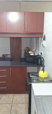 a kitchen with wooden cabinets and a stove top oven at Chrysantimum Guest Apartment in Thabazimbi
