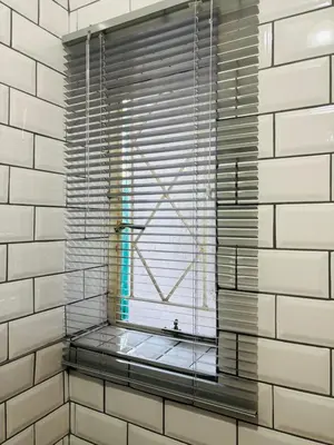 a window with blinds in a white tiled bathroom at The Secret Location in Pretoria