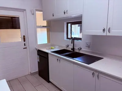 a kitchen with white cabinets and a sink and a window at Pecanwood Villa with lake view in Hartbeespoort