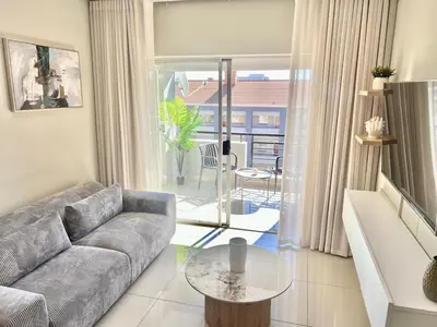 a living room with a couch and a glass table at La Genèse - S507 at Glen Park in Pretoria