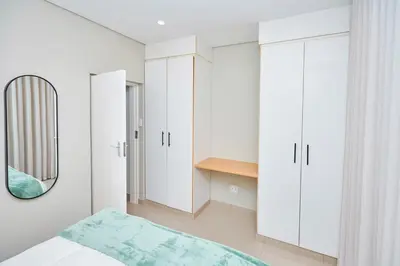 a bedroom with white cabinets and a mirror at La Genèse - S507 at Glen Park in Pretoria