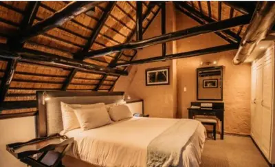 a bedroom with a bed and a desk in it at Mount Sheba Rainforest & Resort in Pilgrimʼs Rest