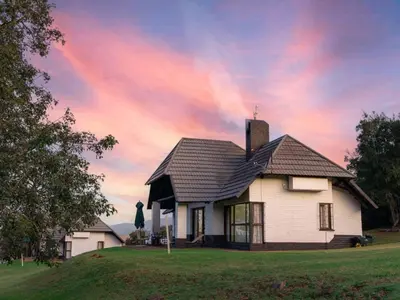 a house on a hill with a cloudy sky at Mount Sheba Rainforest & Resort in Pilgrimʼs Rest