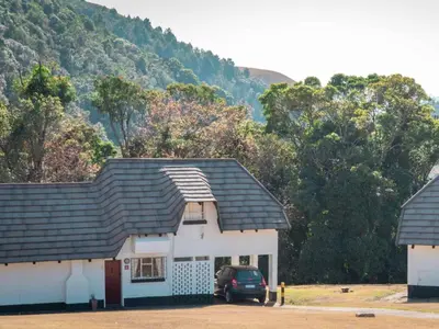 a white house with a car parked in front of it at Mount Sheba Rainforest & Resort in Pilgrimʼs Rest