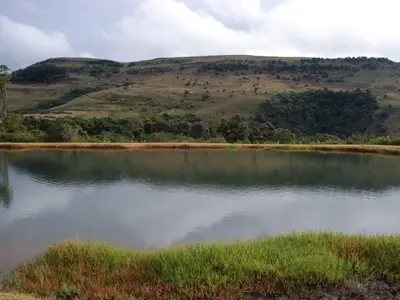 a large body of water with a hill in the background at Mount Sheba Rainforest & Resort in Pilgrimʼs Rest