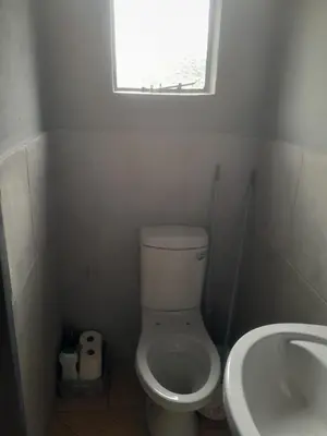 a bathroom with a toilet and a sink and a window at Twala trails lodge in Midrand