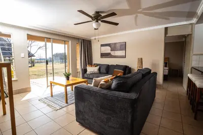 a living room with two couches and a ceiling fan at Carousel Eco Estate in Temba