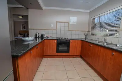 a kitchen with wooden cabinets and a sink and a stove at Carousel Eco Estate in Temba